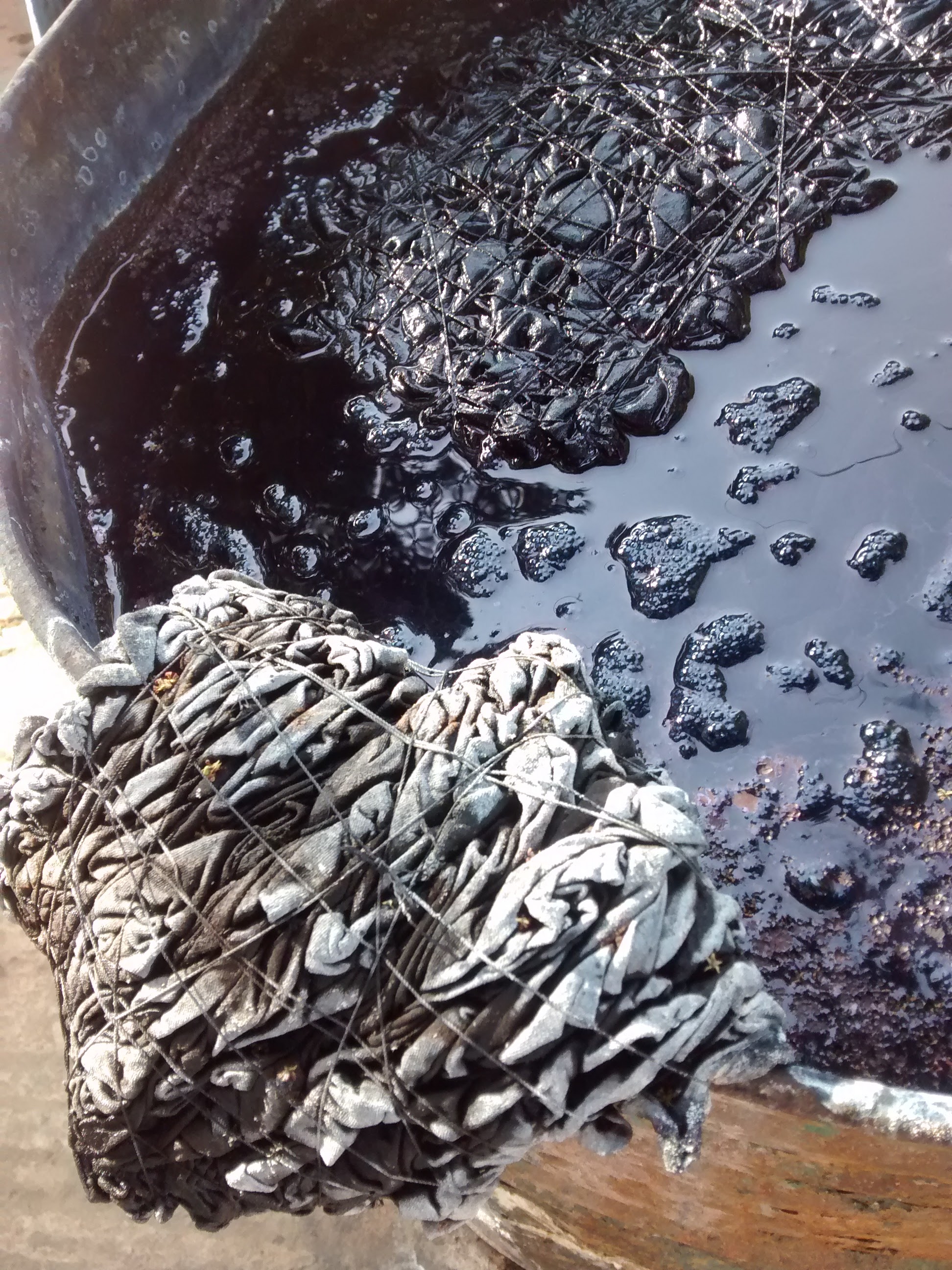 Beautifully intricate tie dyed fabric soaking in indigo dye. It will seep for 3 days before being rinsed, washed and dried. Then it will be completely colourfast.
