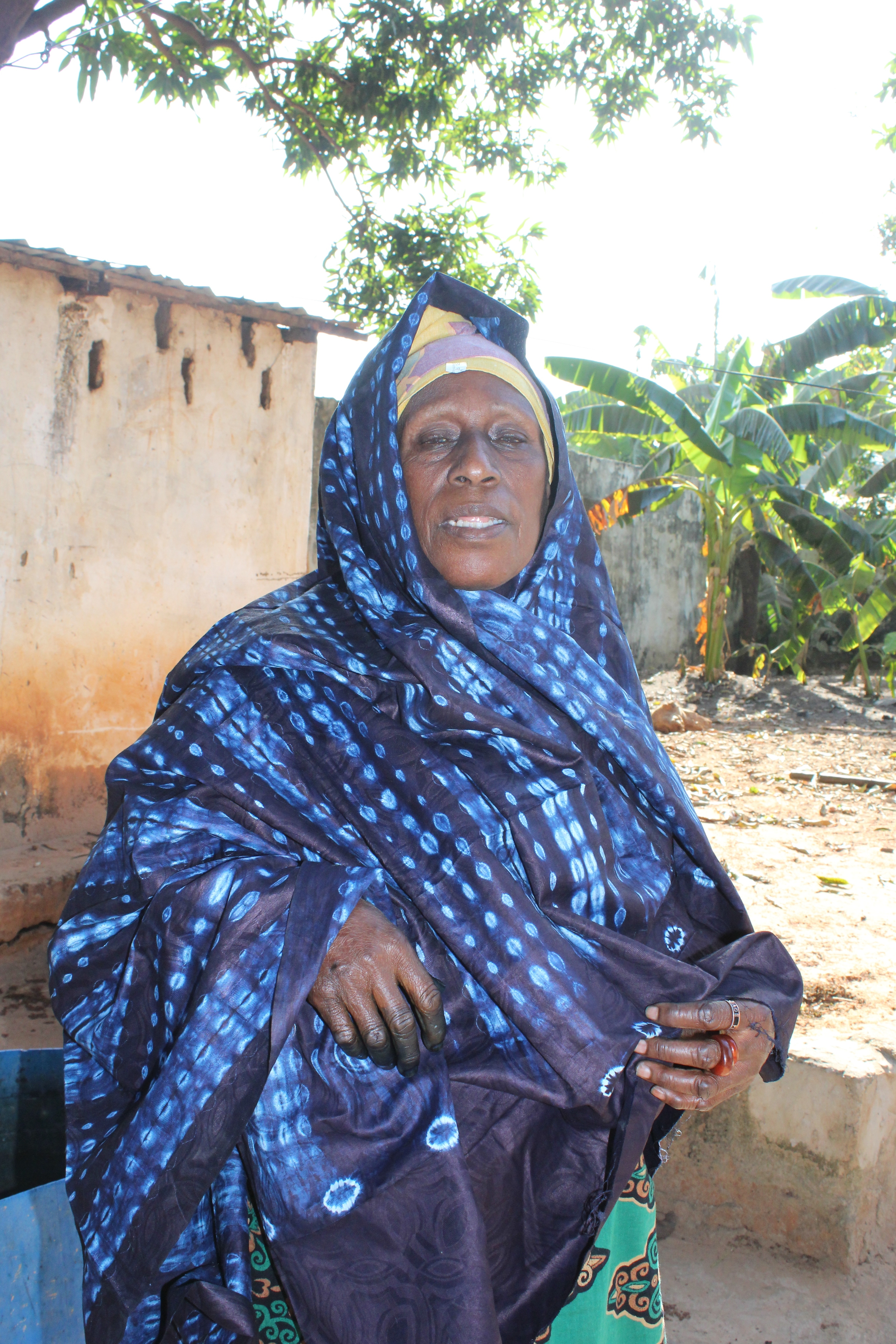 Nafri (sp) the matriach expertly models a piece of finished tie dyed indigo cloth, her own handiwork. Usually worn as a skirt.